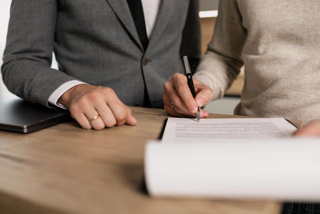 A person signing a lease as someone else watches