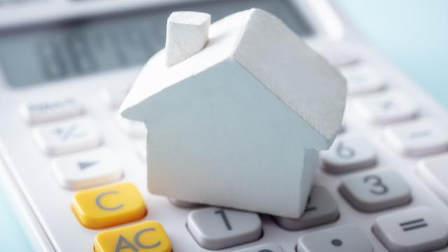 a small home figurine on top of a calculator