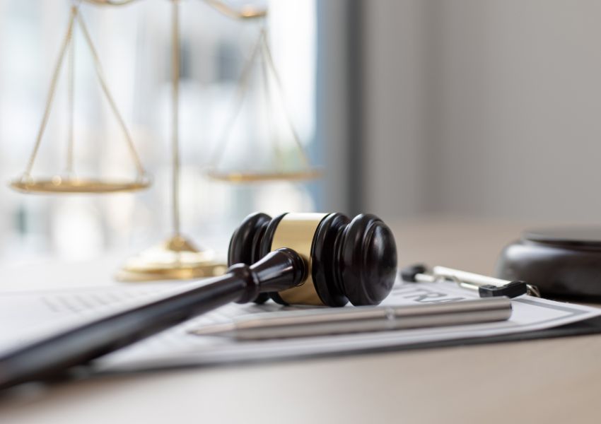 judges gavel on top of a clipboard with a legal balance in the background